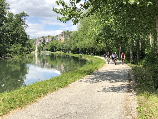 une groupe de cyclistes au bord du canal du nivernais avec le rocher du saussois en arriere plan